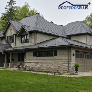 A beautiful house with a grey metal roof, stone and siding exterior, attached garage, and the Roof Pros Plus logo in the corner, which is an expert in metal roof installation and quality roofing materials.