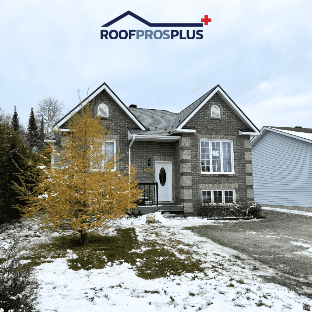 An image of a suburban home with a brick facade, surrounded by light snow on the ground. The house features white-framed windows, a small front porch, and a galvanized metal roof. A golden-yellow tree adds contrast to the snowy scene. The 'Roof Pros Plus' logo is displayed at the top of the image.