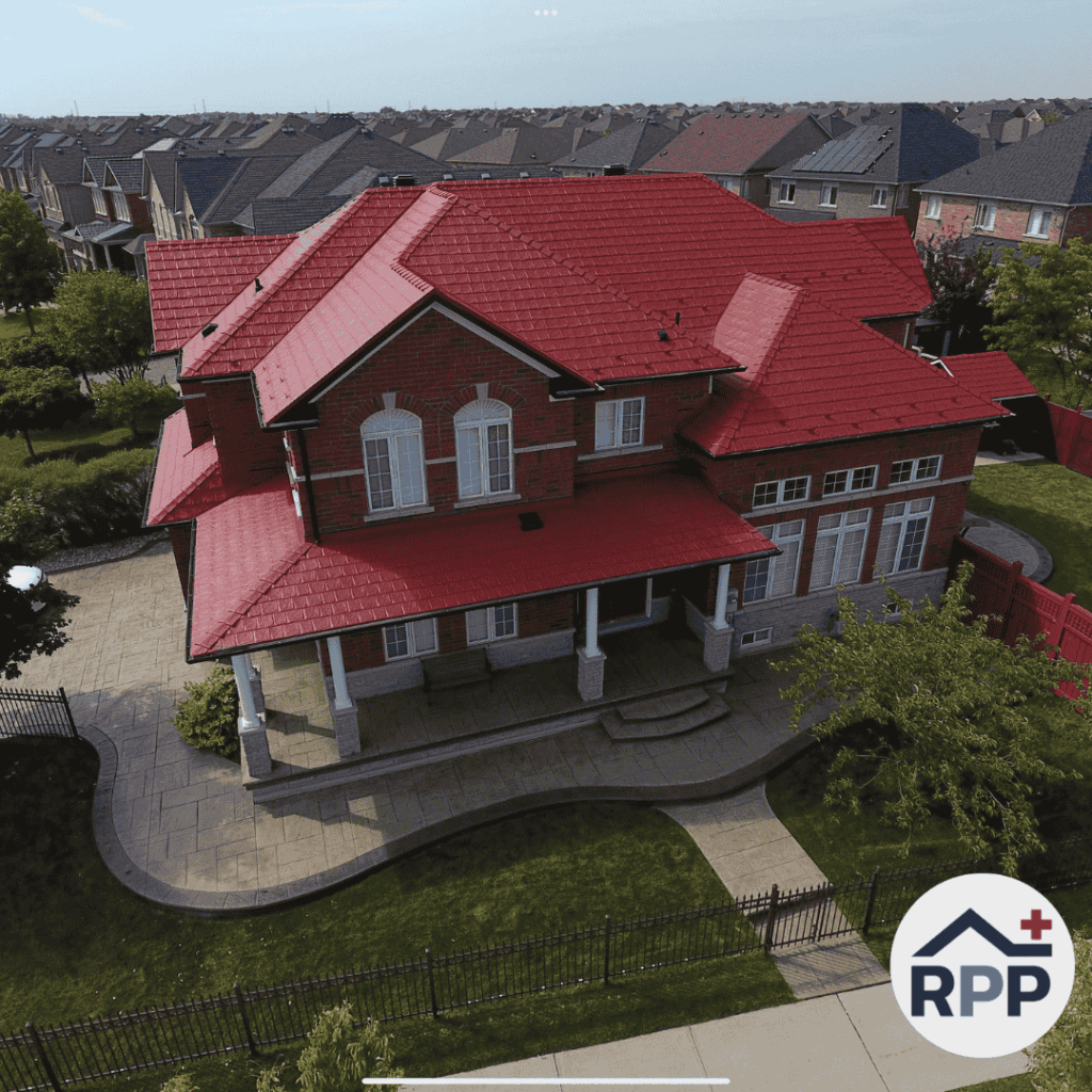 Aerial view of a large two-storey brick home with a bright red metal roof, covered front porch, and landscaped front yard, surrounded by similar suburban houses. RPP logo appears in the bottom right corner.