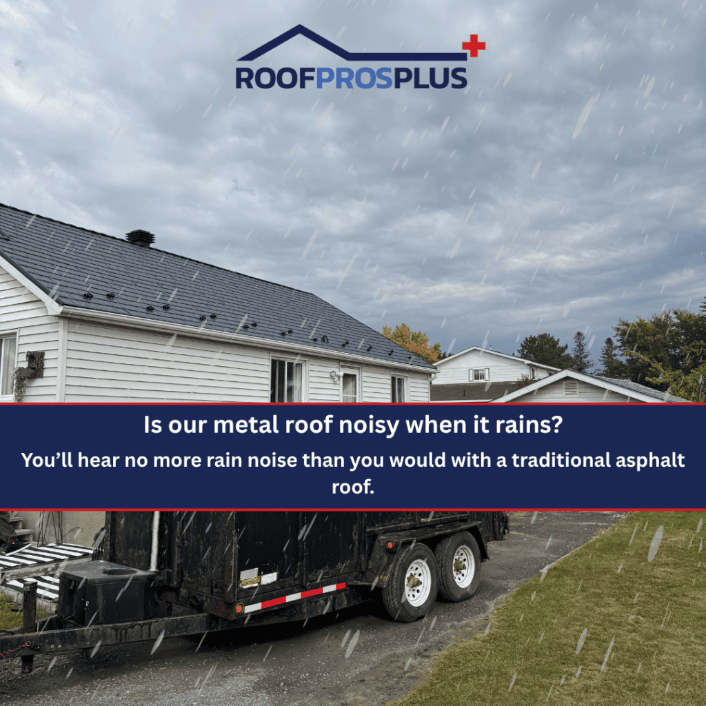 A white house with a dark metal roof in the rain, with a trailer in the driveway and trees in the background. The text on the image says, "Is our metal roof noisy when it rains? You'll hear no more rain noise than you would with a traditional asphalt roof."