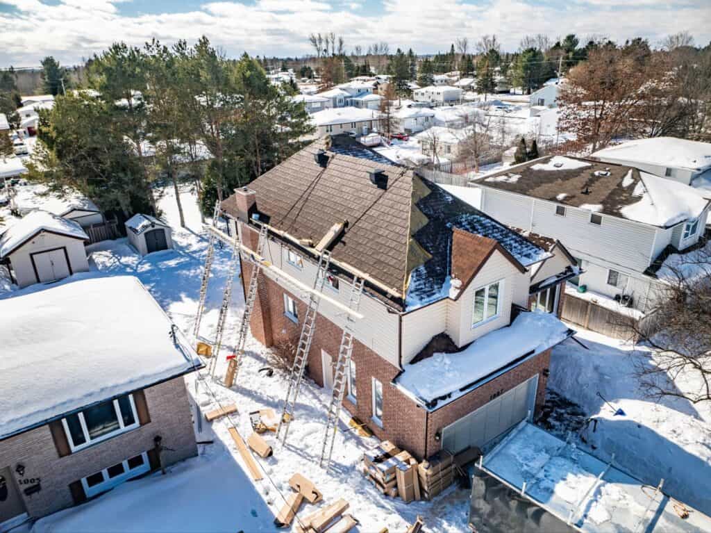 A residential home undergoing a metal roof installation by Roof Pros Plus during winter.