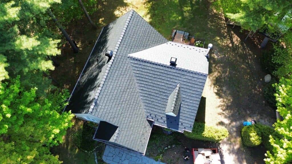 Aerial view of a premium dark grey Armadura metal roof installed by Roof Pros Plus on an Ontario home surrounded by mature trees, highlighting durable residential steel roofing.