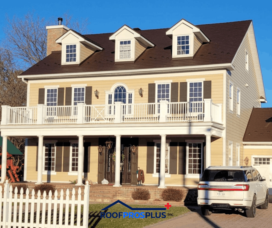 A two-story yellow house with white trim and dark shutters. A white picket fence and an SUV are in front. The sky is clear and blue.